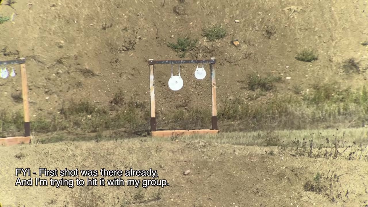 Two white steel plates on a wooden target frame at the 300 yard berm, with on-screen text reading "FYI - First shot was there already, and I'm trying to hit it with my group"
